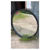 Large round wall mirror with a black frame. A