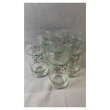 Seven clear drinking glasses featuring a green