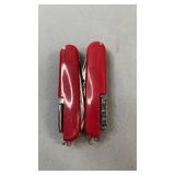 Two red multi-tool pocket knives with various