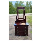 Dark wood three-drawer dresser on wheels with
