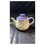 White ceramic teapot decorated with small purple