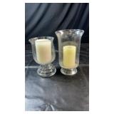 Two clear glass hurricane-style candle holders in