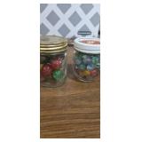 2 small jars with marbles one with larger shooter