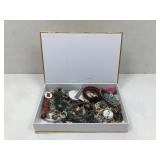 Small gold colored box full of costume jewelry