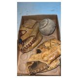 2 baseball gloves and a softball