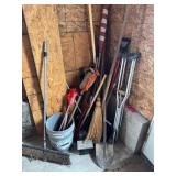 Contents of corner: garden tools, brooms, flag,