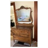 Wooden dresser on wheels with mirror back.