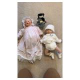 Two baby dolls with small stuffed animal