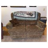 Upholstered patterned loveseat with throw blanket and pillow
