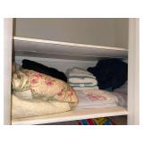Assorted linens and quilt on shelf