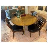 Round dining table with green wooden base and 6 chairs on casters