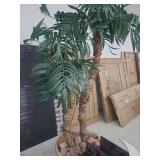 lot contains a 6ft artificial palm tree in a tan colored decorative pot with rocks.