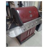 lot contains a Kenmore 4 burner propane gill with a side burner, cutting board,  grill scrubber, and stainless steel spatula.