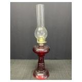 Red glass base oil lamp w/clear globe, 18in tall.