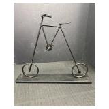 Metal bicycle sculpture mounted on metal base,