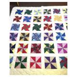 A machine-stitched pinwheel quilt. It measures 97
