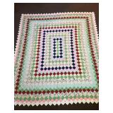 A hand-stitched quilt. It measures approx. 84 x