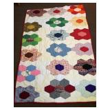 A hand-stitched quilt. It measures approximately