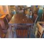 Tall dining table with leaf and six chairs.