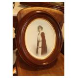 Oval walnut frame containing a hand colored photo