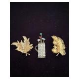 2 Gold toned leaf brooches and a golf bag