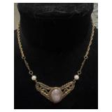 cabochon stone set within an ornate, leafy
