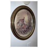 oval gold plastic picture frame with a cottage in