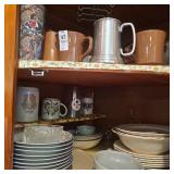 Two shelves of assorted dishes,  coffee mugs,