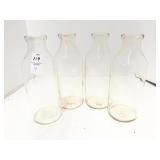 Four glass milk bottles, 10 inches tall