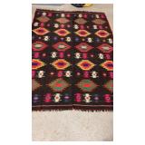 Black Turkish kilim rug features a zigzag border