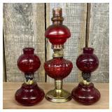 A Trio of Ruby Red Glass Oil Lamps Including Plume