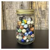 A Collection of Vintage Glass Marbles in a Graduat