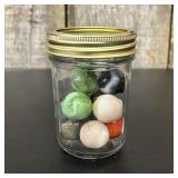 A Collection of Vintage Glass Marbles in a Graduat