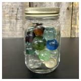 A Collection of Vintage Glass Marbles in a Graduat
