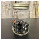 A Collection of Black Glass Cat Eye Marbles in a G