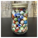 A Collection of Vintage Glass Marbles in a Graduat