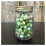 A Collection of Vintage Glass Marbles in a Graduat