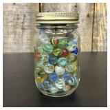 A Collection of Vintage Glass Marbles in a Graduat