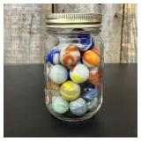 A Collection of Vintage Glass Marbles in a Graduat