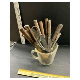 Measure cup with vintage knives and other