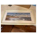 Framed lighthouse and sailboat picture.