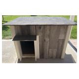 Outdoor wooden dog house with hinged lid,