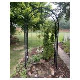 Arched black steel garden arbor featuring