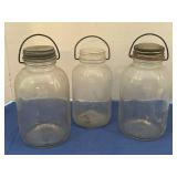 Three vintage clear glass jars with wire handles.