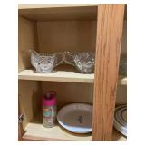 Two shelves of clear glass and Corningware and Corelle