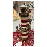Holiday lighthouse with bright rotating light and Santa and his reindeer flying around the lighthouse w/box