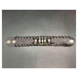 Black leather-like snap bracelet enhanced with skulls and ammo-like accents in center….band shows slight wear from normal use