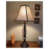 Traditional table lamp featuring a dark bronze-like finish, metal scroll base with marble-like cylindrical accent and a beige flare shade….25-1/2” tall