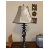 Traditional table lamp featuring a dark bronze-like finish, metal scroll base with marble-like cylindrical accent and a beige flare shade….25-1/2” tall