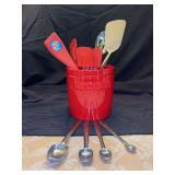 Red stone are utensil crock with kitchen utensils and set of silver metal measuring spoong